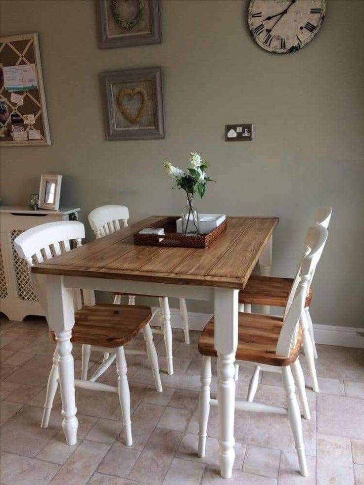 a wooden table with white chairs and a clock on the wall above it in a dining room