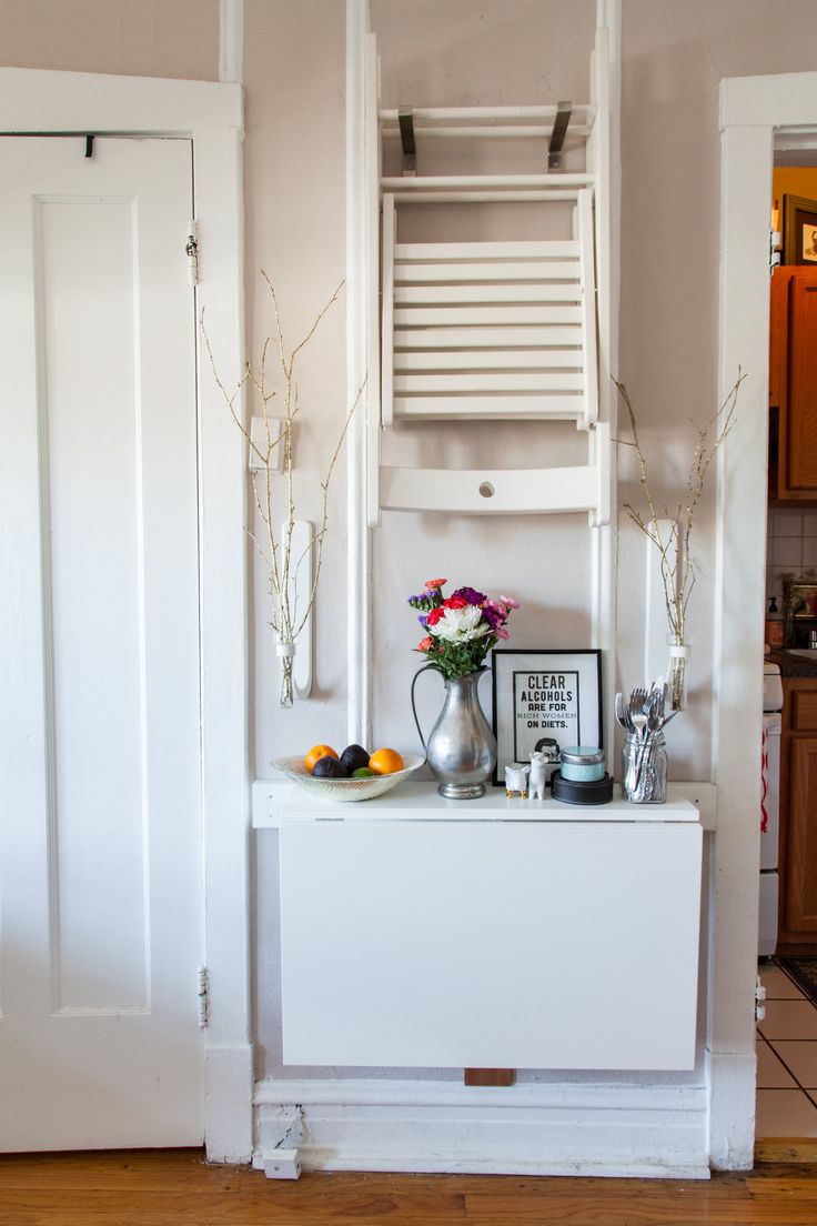 a white cabinet sitting in the corner of a room next to a door with flowers on it