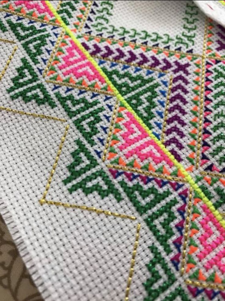 a close up of a cross stitch pattern on a piece of cloth with scissors in the background