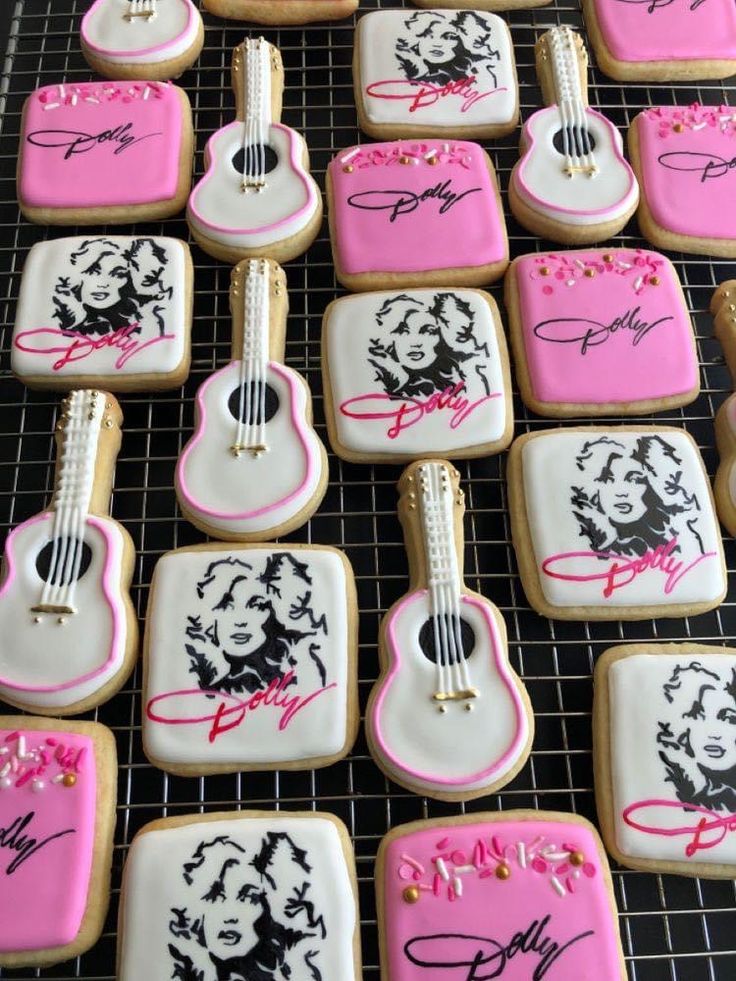 decorated cookies are arranged on a cooling rack with pink and black icing, including guitars