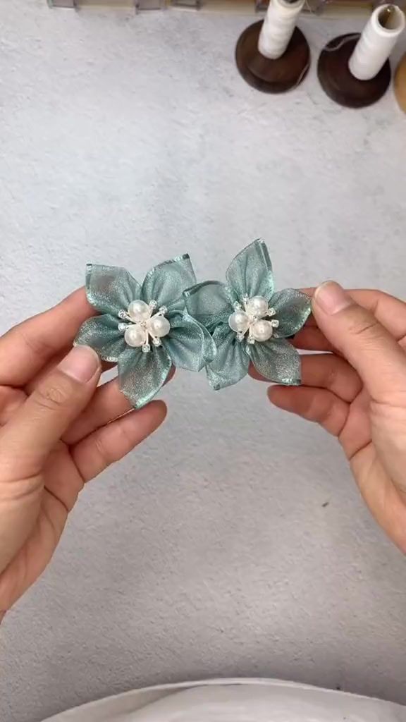 two hands are holding some fabric flowers