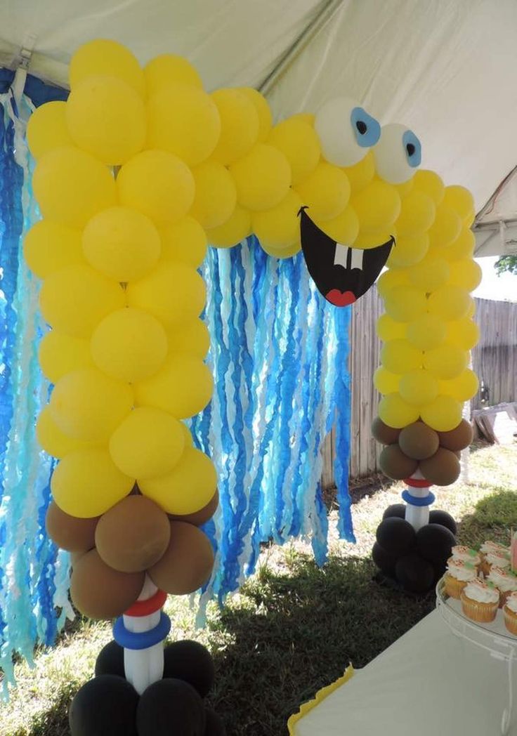 some balloons are hanging from the ceiling in front of a table with cupcakes on it