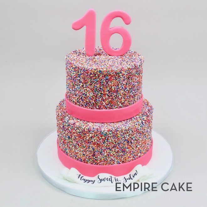 a three tiered cake with pink frosting and sprinkles on top