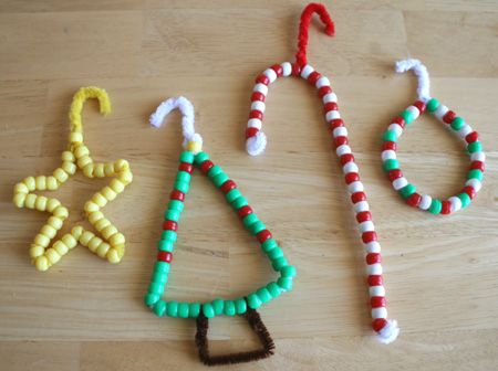 three christmas ornaments made out of candy canes on a wooden table with other items