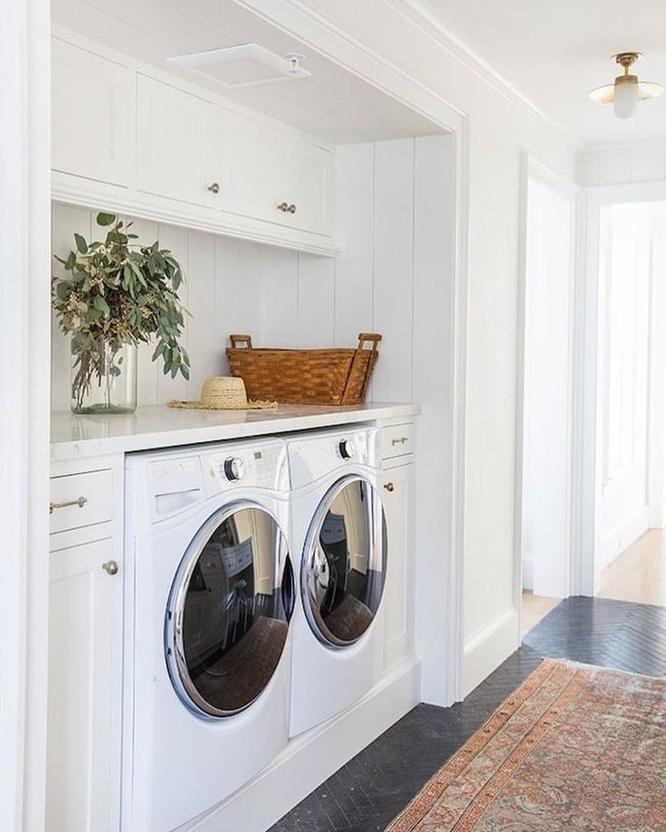 a washer and dryer in a white laundry room with an area rug on the floor