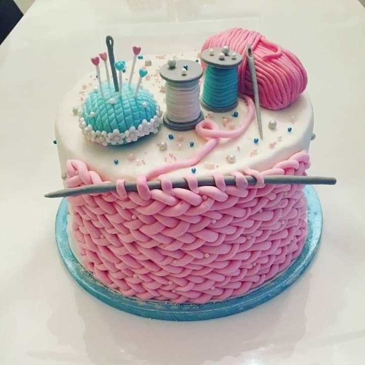 there is a cake that has yarn and knitting needles on top of it, along with two spools of thread