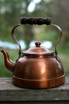 a copper tea kettle sitting on top of a wooden table