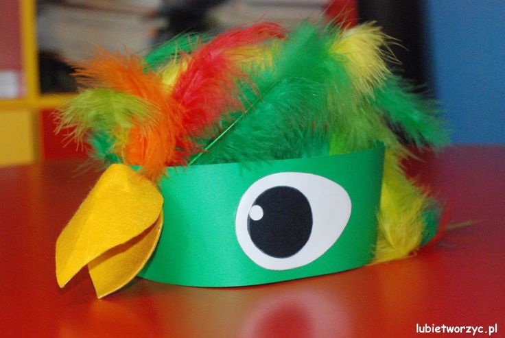 a green paper hat with an eyeball and feathers on the top, sitting on a table