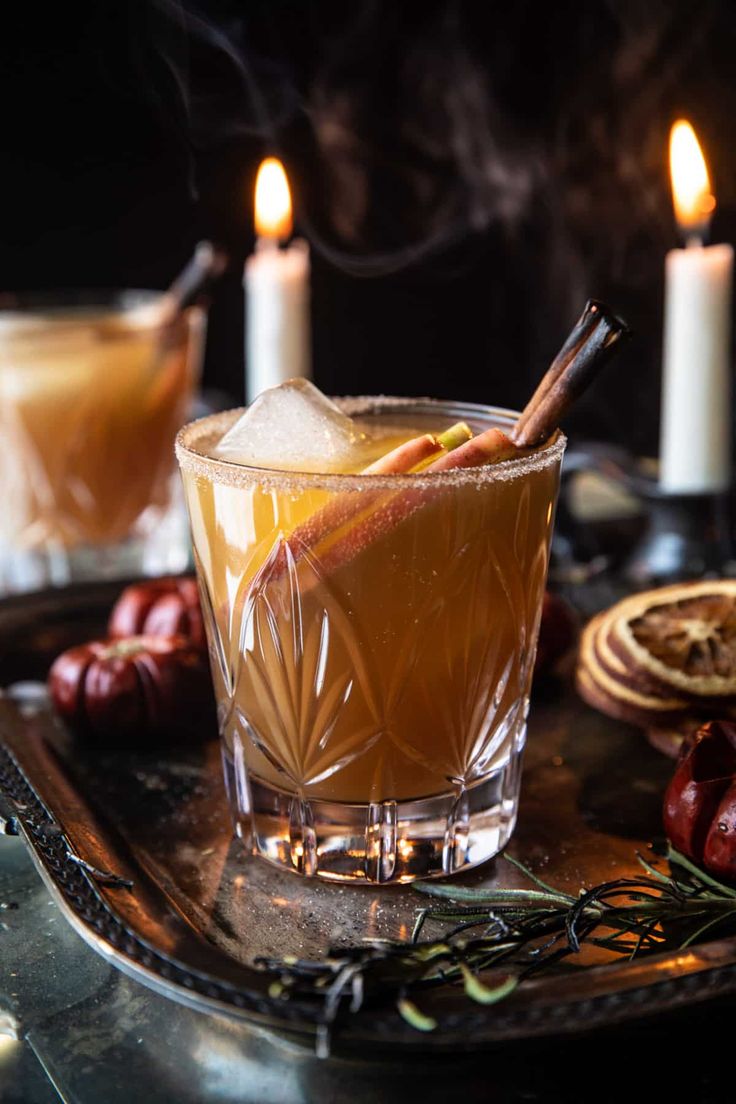 a glass filled with liquid sitting on top of a metal tray next to two lit candles