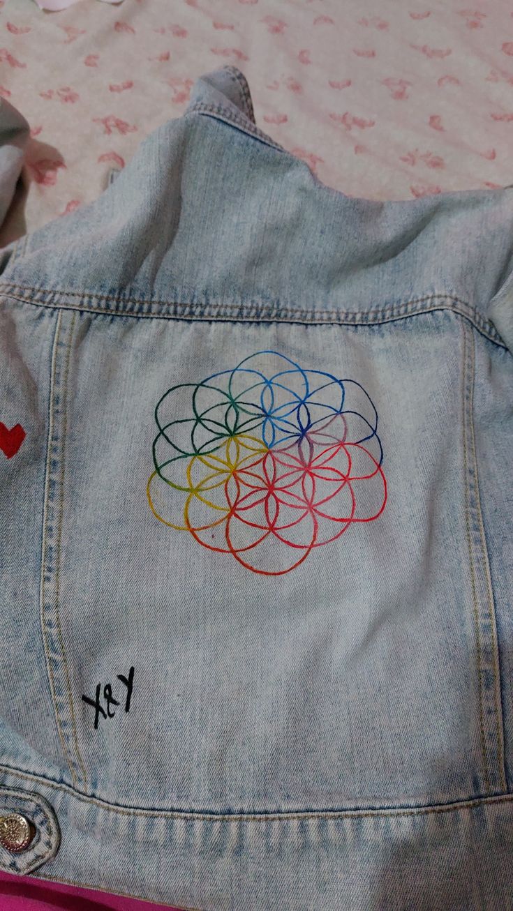 the back of a jean jacket with an embroidered rainbow circle on it