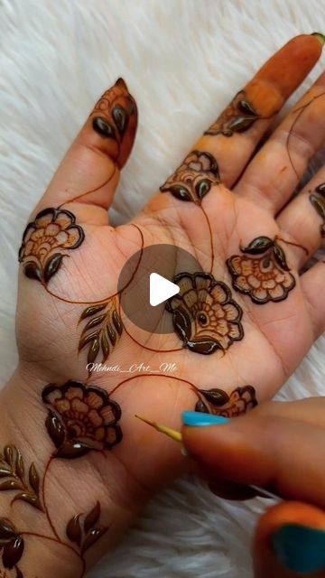 a woman's hands with henna tattoos on them and flowers painted on the palm