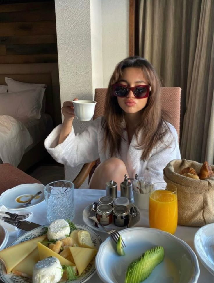 a woman sitting at a table with food and drinks