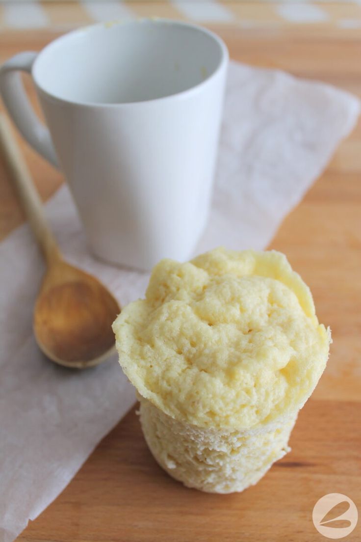 a close up of a muffin on a table with a cup of coffee in the background