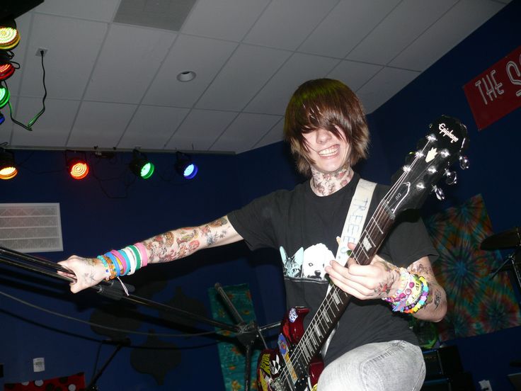 a man with tattoos on his arms playing an electric guitar in front of a microphone