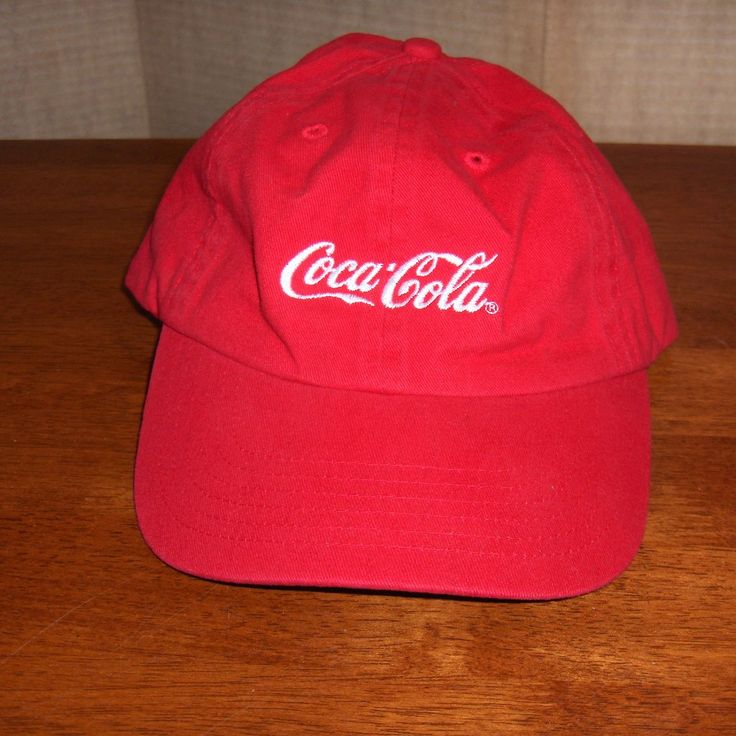 a red coca cola hat sitting on top of a wooden table