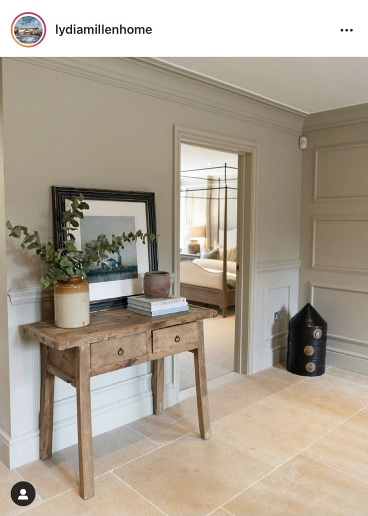 a wooden table sitting in the middle of a room next to a mirror and vase