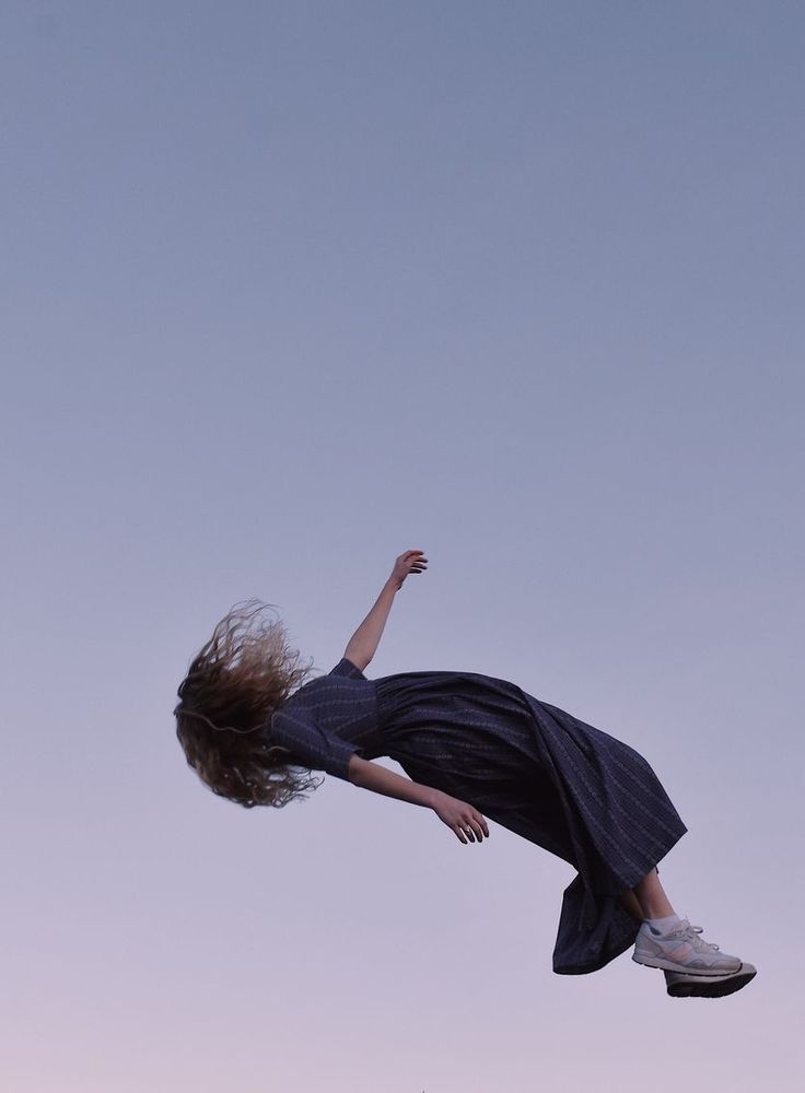 a woman flying through the air while riding a skateboard in front of a blue sky