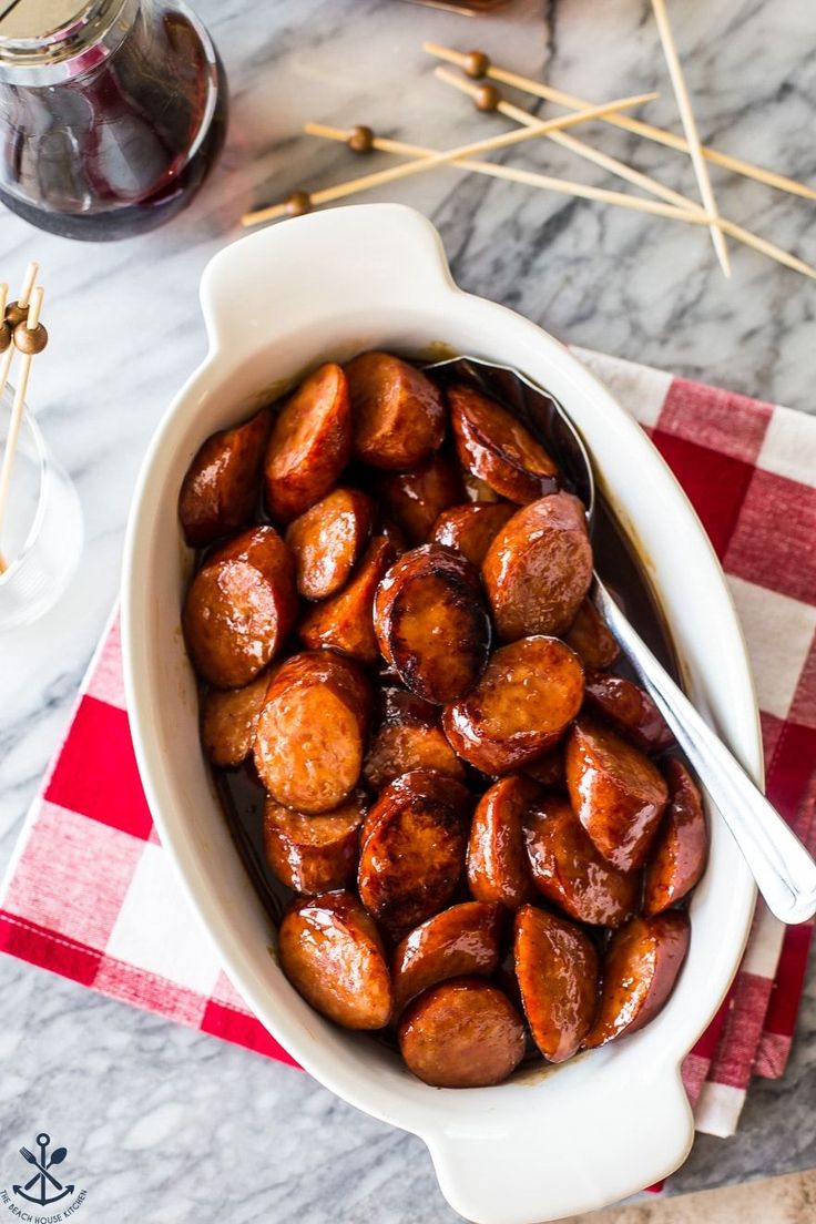 a bowl filled with cooked sausage on top of a red and white checkered table cloth