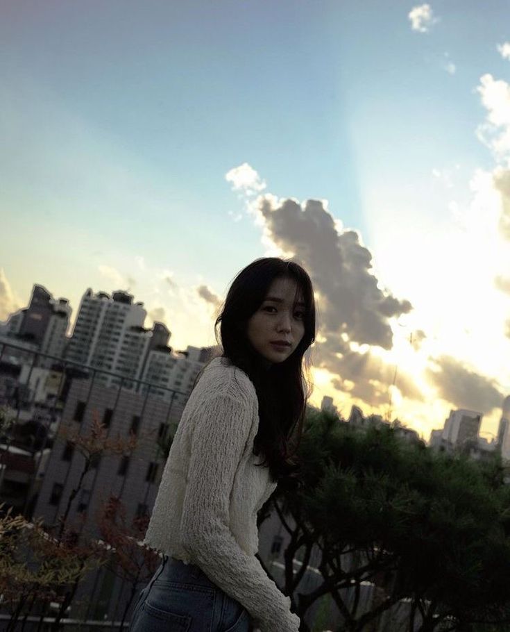 a woman standing on top of a roof next to a tall building with buildings in the background