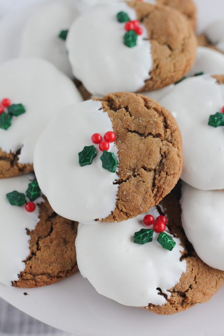 cookies with white frosting and red berries on them are arranged on a plate, ready to be eaten