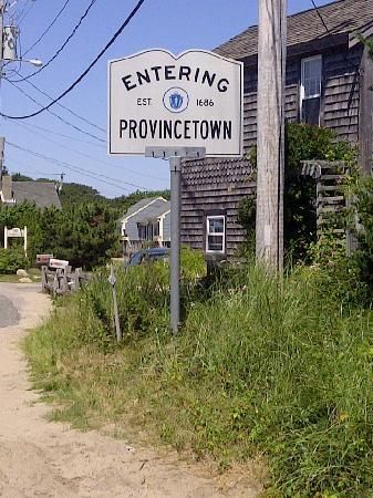 a street sign on the side of a dirt road in front of some wooden houses