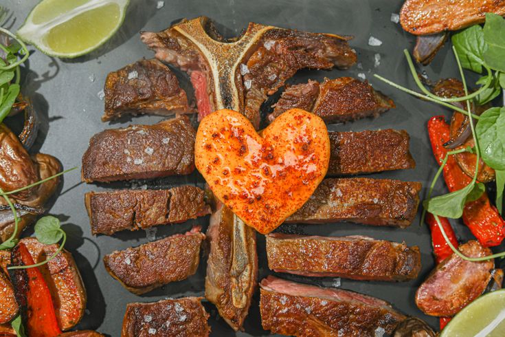 steaks and vegetables arranged in the shape of a heart