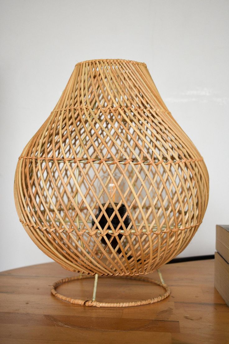 a wicker vase sitting on top of a wooden table next to a small box