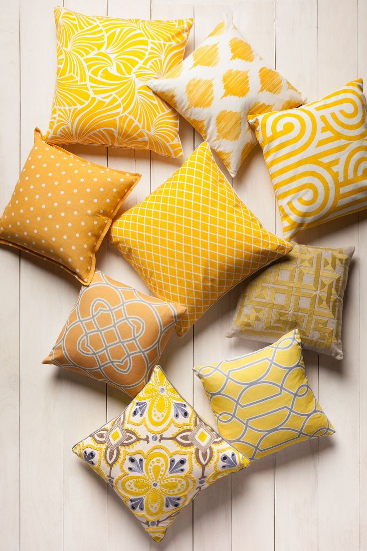 several yellow and white pillows arranged on a wooden floor, with one pillow in the middle