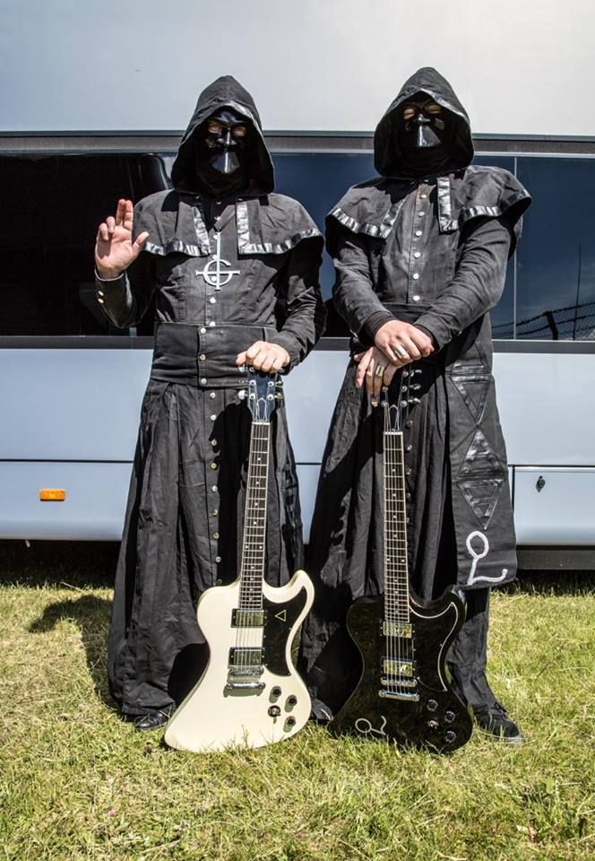 two people dressed in black are holding guitars