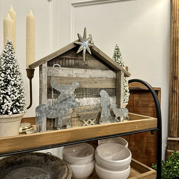 a shelf with dishes and candles on it in front of a christmas tree, snowflakes and other decorations