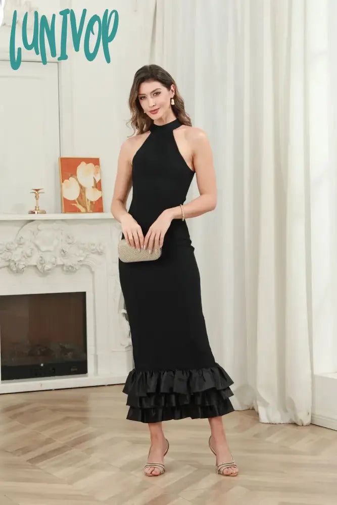 a woman standing in front of a fireplace wearing a black dress with ruffles