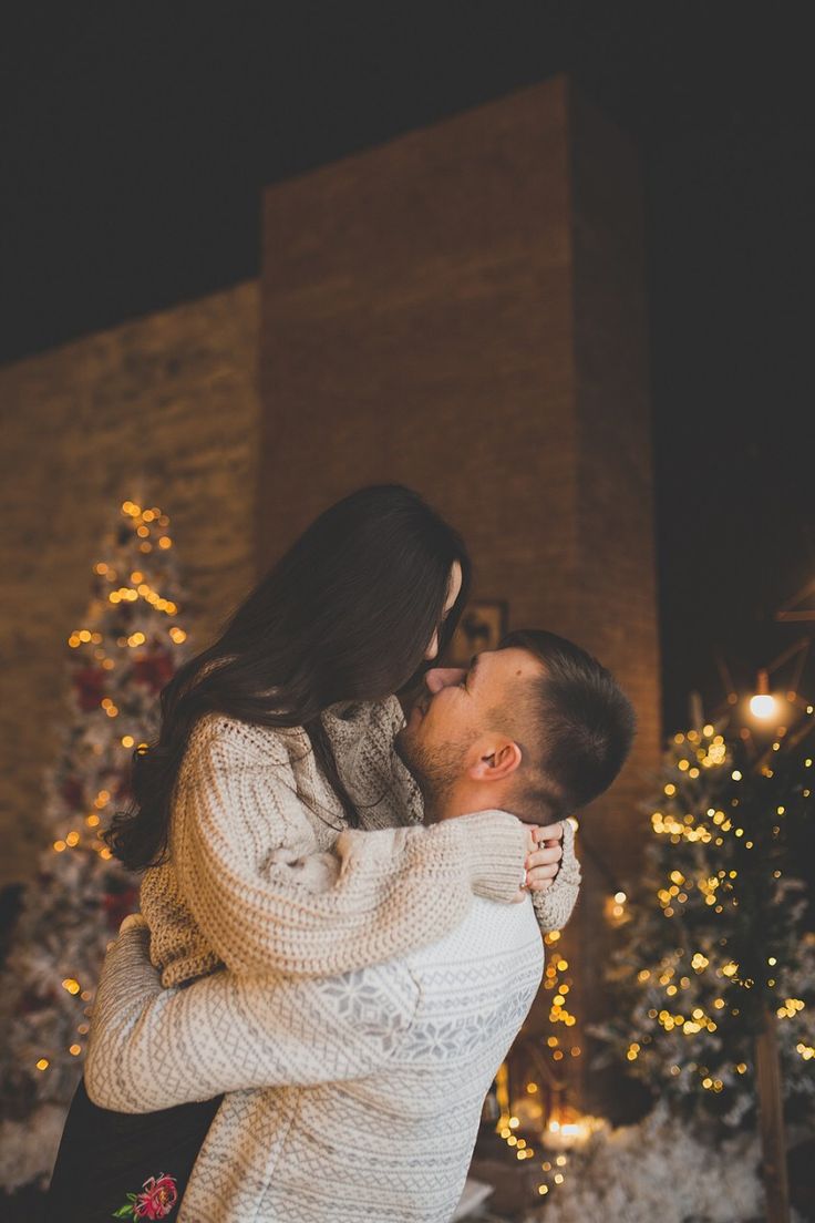 a man and woman kissing in front of a christmas tree