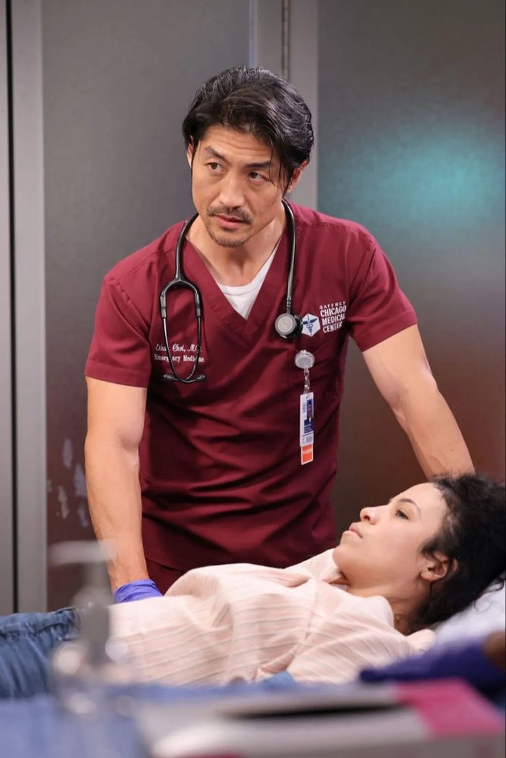 a man in scrubs standing next to a woman on a bed