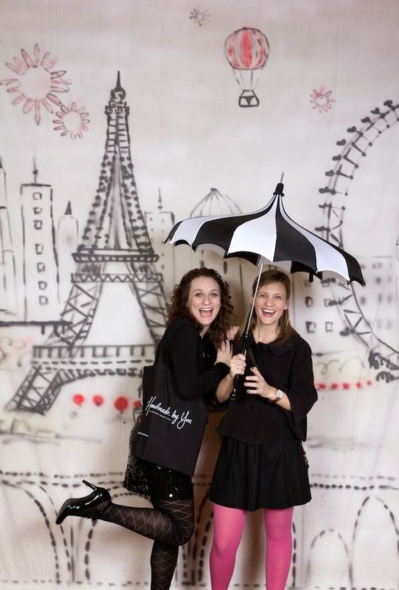 two women standing next to each other with umbrellas in front of the eiffel tower