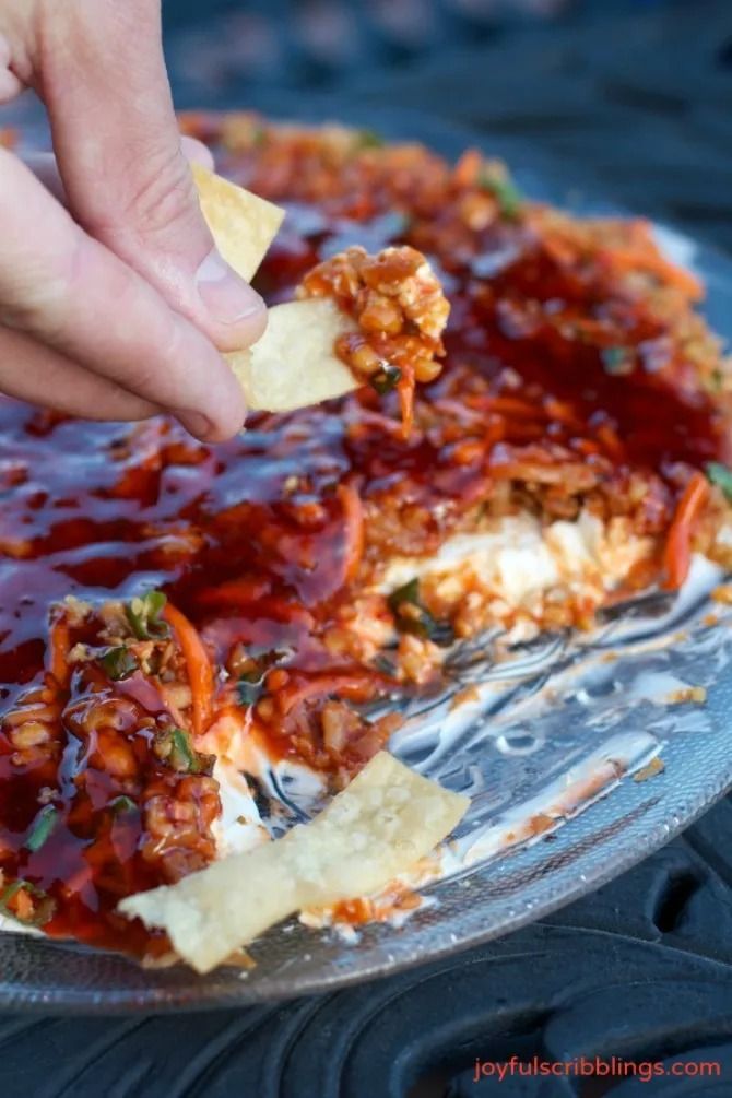 someone is dipping some chips into a pizza crust covered in ketchup and relish