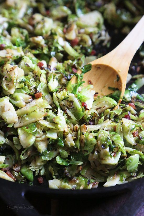 a wooden spoon in a bowl filled with broccoli sprouts and raisins