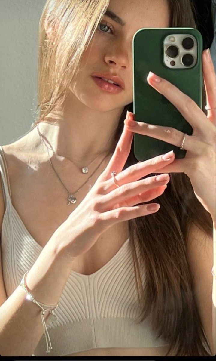 a woman holding up her cell phone to take a selfie with her hand and arm