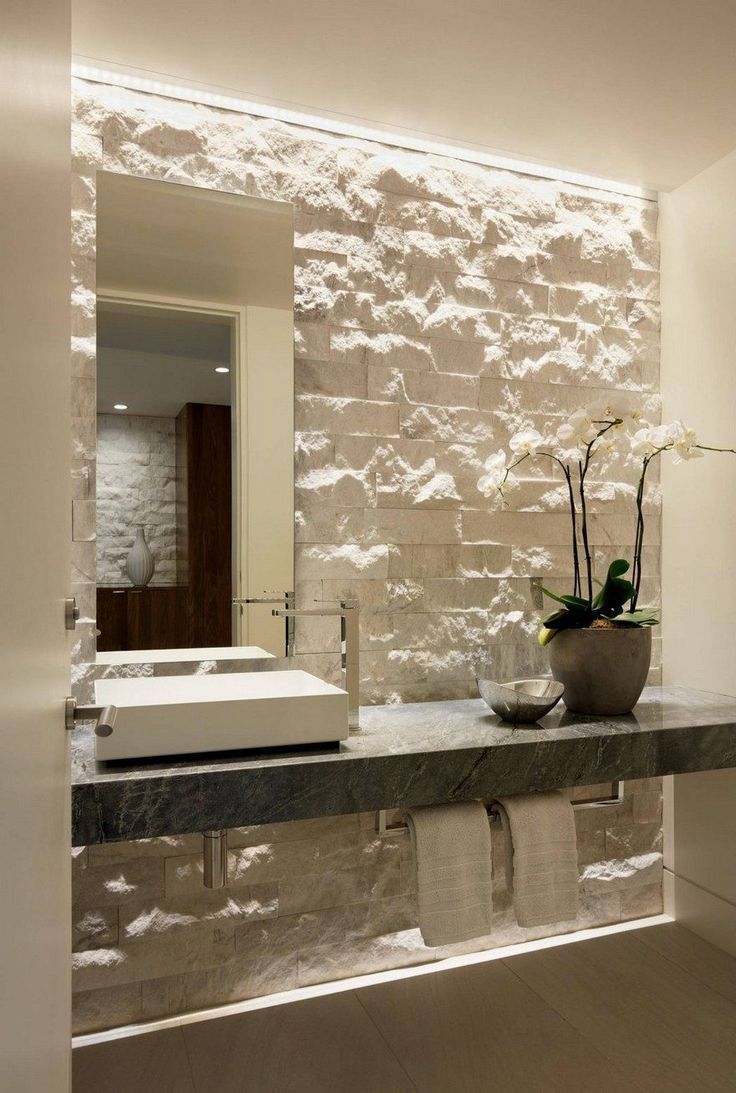 a bathroom with stone walls and a white sink in front of a mirror on the wall