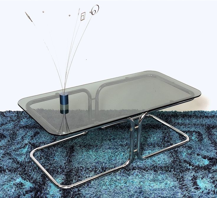 a glass table with some sort of object on it's top, sitting on a blue rug