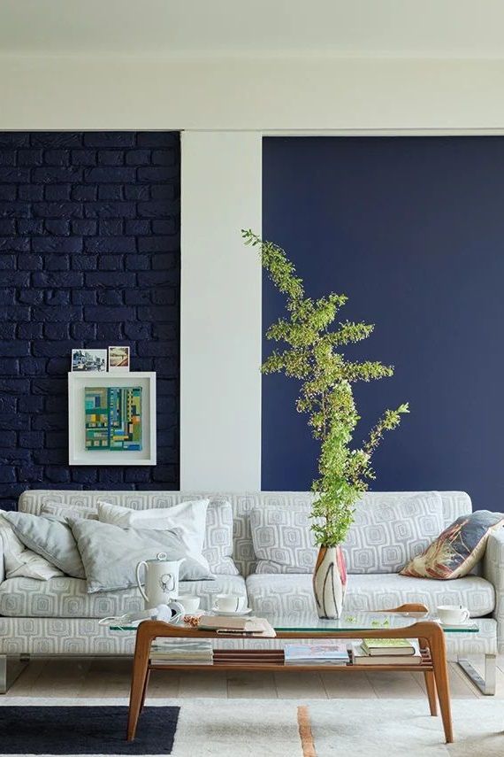 a living room filled with furniture and a blue brick wall behind the couch is a coffee table