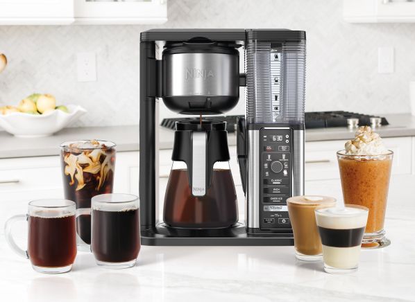 a coffee maker sitting on top of a kitchen counter next to cups and glasses filled with liquid