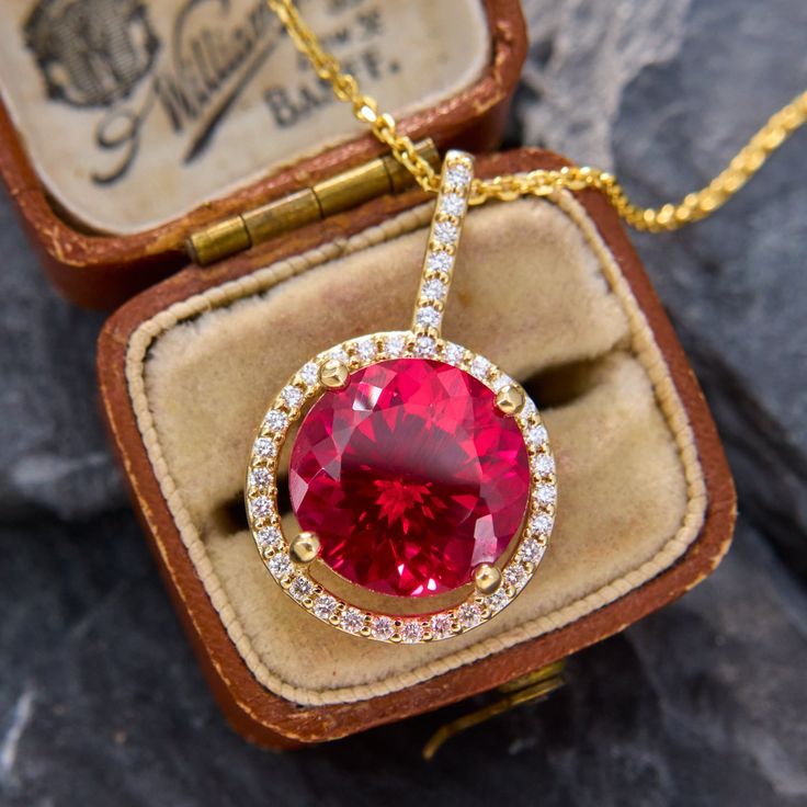 This sparkling pendant necklace is centered with a large round lab created ruby cut to brilliant perfection. Surrounding the ruby and climbing up the bale are thirty-six round brilliant cut diamonds, all set in 14k yellow gold. The pendant hangs from 14k yellow gold, 18 inch long cable chain with jump rings so it can also be worn at 16 and 17 inches as well. Luxury Lab-created Ruby Necklace Gift, Fine Jewelry Ruby Diamond Necklace Brilliant Cut, Red Diamond Necklace With Brilliant Cut, Dazzling Jewelry With Brilliant Cut Lab-created Ruby, Brilliant Round Cut Lab-created Ruby Jewelry, Red Diamond Cut Diamond Necklace, Red Diamond Cut Diamond Necklaces, Red Diamond Cut Necklace, Red Diamond Cut Necklaces