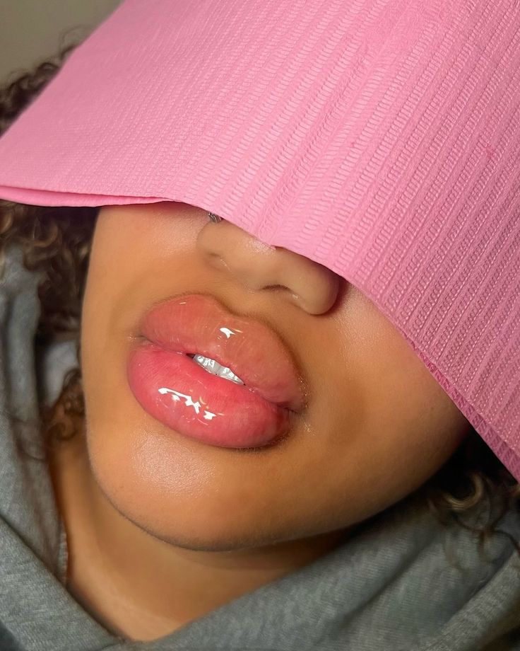 a young child wearing a pink hat with her tongue sticking out from under the visor