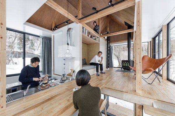 two people are sitting at the kitchen counter looking out onto the living room and dining area