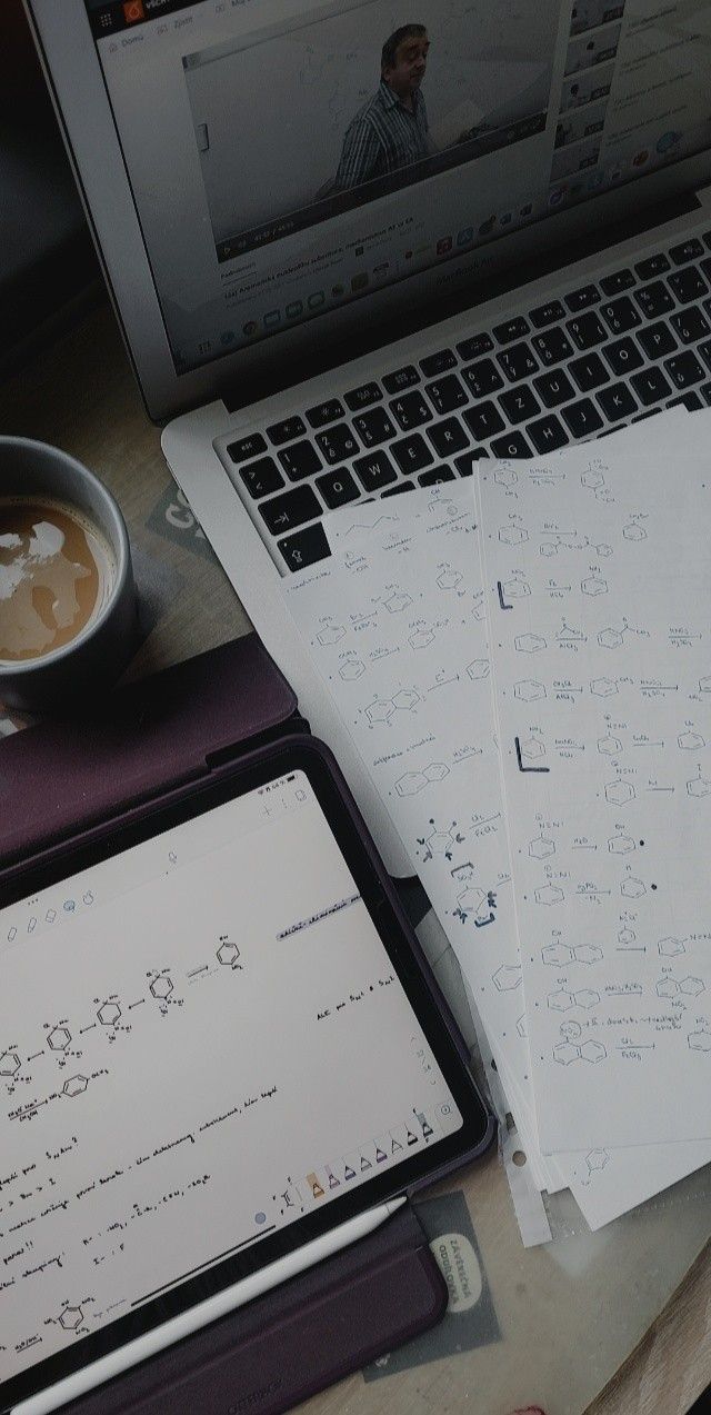 a laptop computer sitting on top of a desk next to papers and a cup of coffee