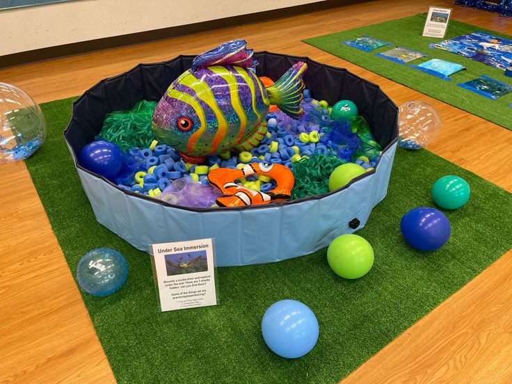 an inflatable fish is surrounded by balls and other toys on the floor at a children's museum