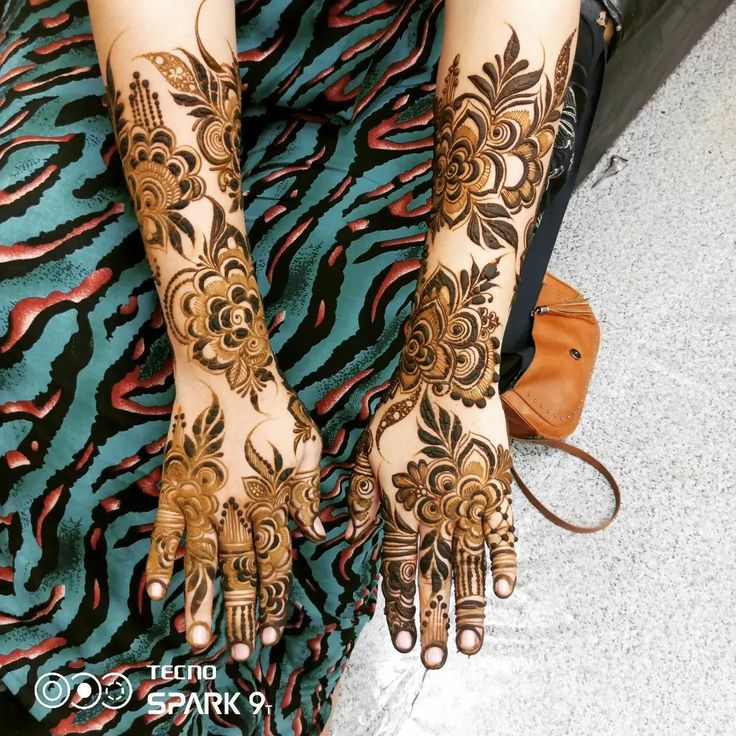 a woman's hands and feet with henna tattoos on their arms, both decorated with flowers