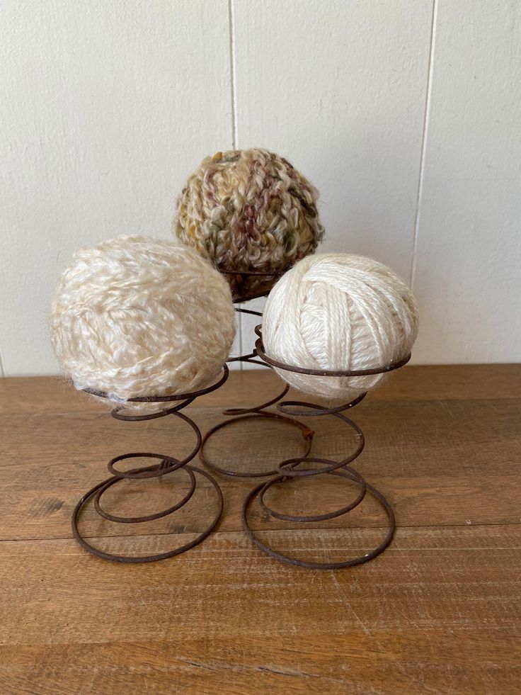 three balls of yarn sitting on top of a metal stand