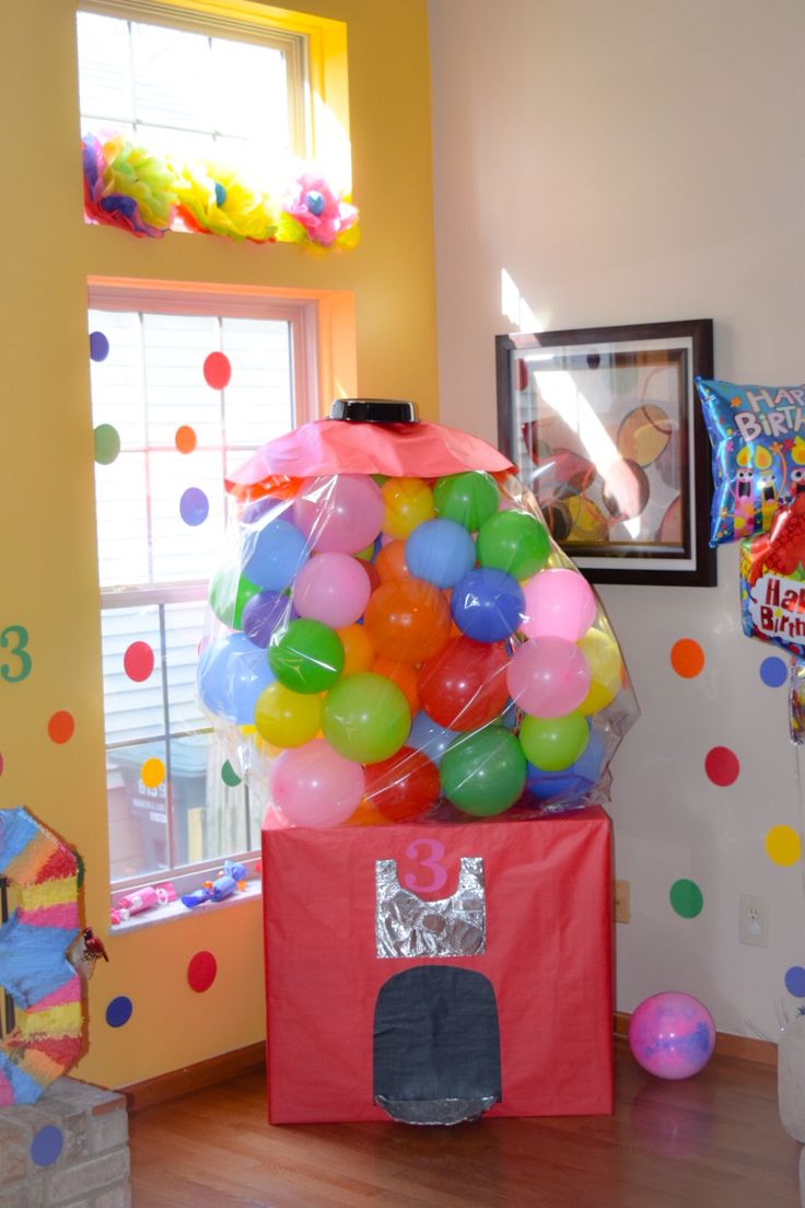 a room filled with balloons and toys in front of a window on top of a hard wood floor