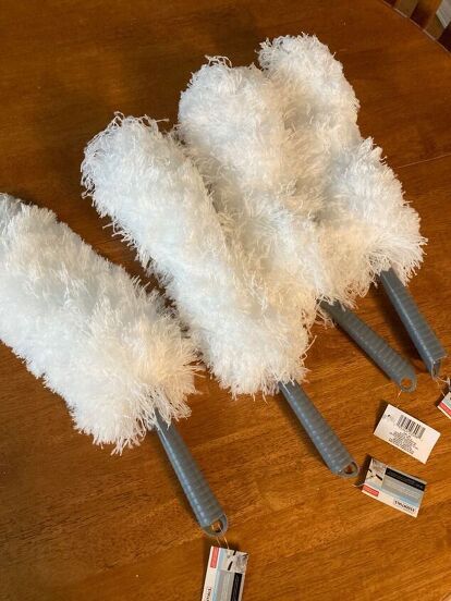 three white feathers on top of a wooden table next to some scissors and tags with price tags